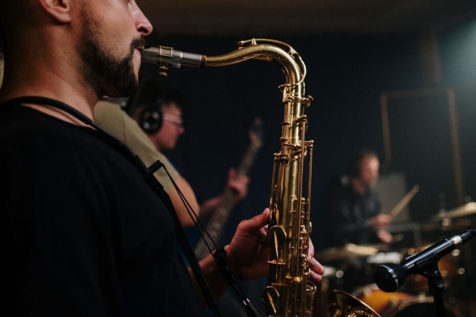 Saxofonist speelt tijdens een donkere jazzsessie met andere muzikanten