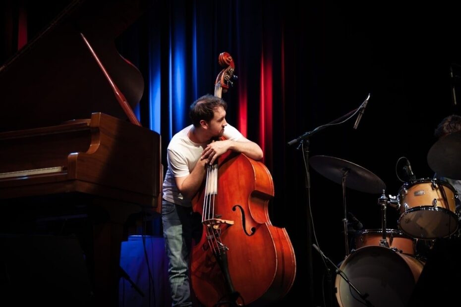 Contrabassist naast piano en drumstel op een jazzpodium