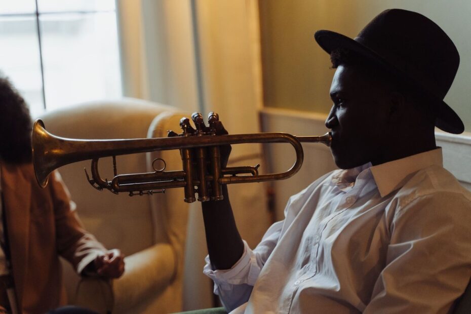 Jazzmuzikant met hoed speelt trompet in een warme, schemerige kamer